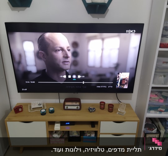 טלוויזיה תלויה על הקיר עם מדף מתחתיה